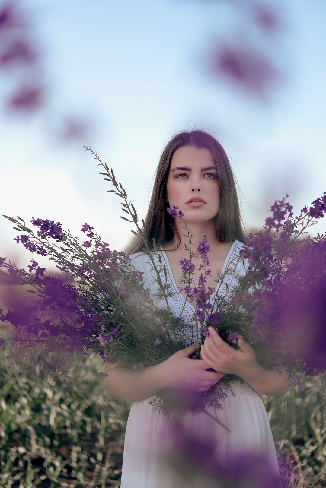 Mulher segurando flores roxas, representando a marca Bioma Care.